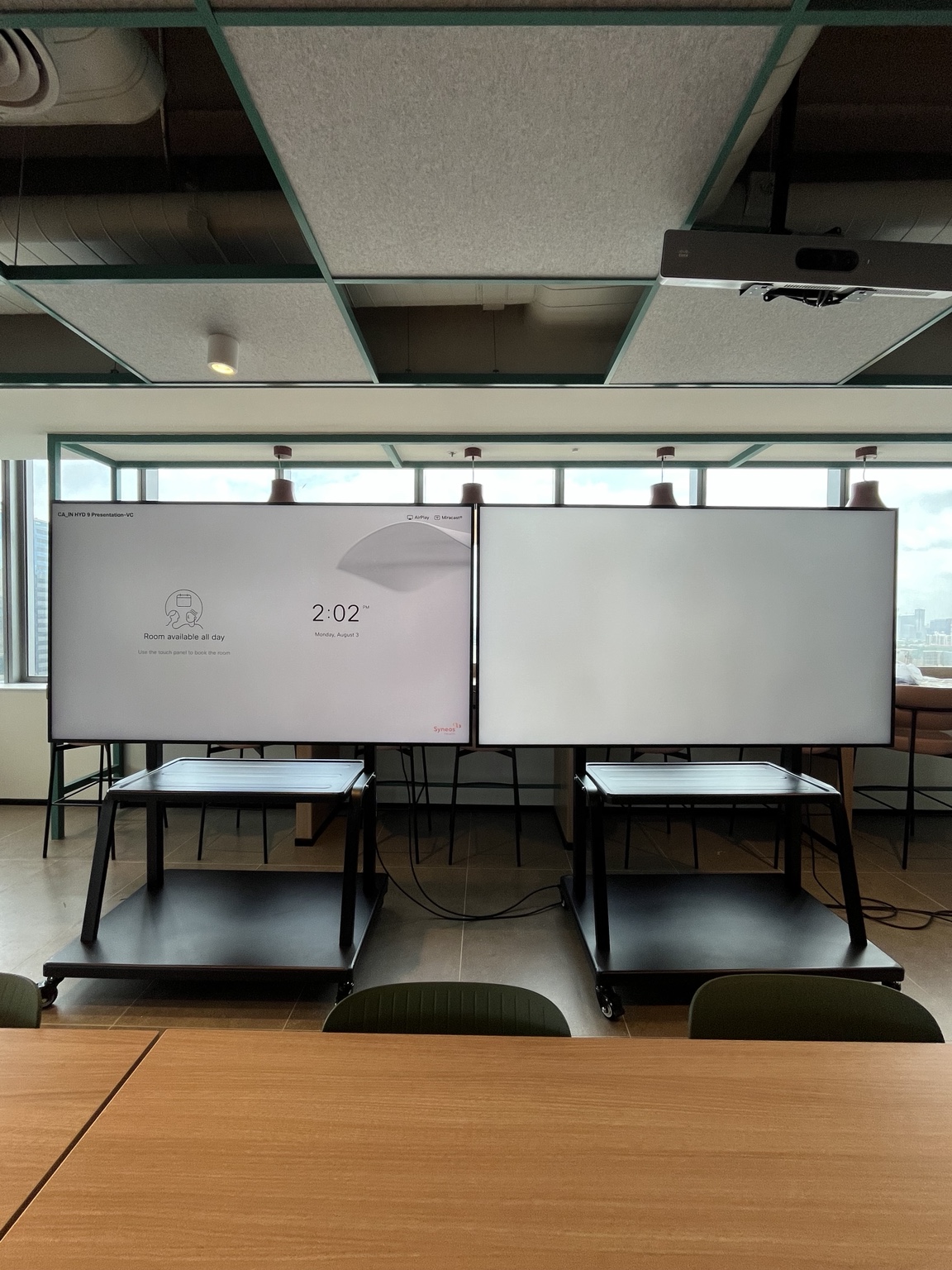 A dual-display presentation setup with a ceiling-mounted camera for shared gathering spaces.